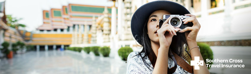 Southern Cross Travel Insurance - member offer A woman on holiday in Asia, taking a photo of her surroundings